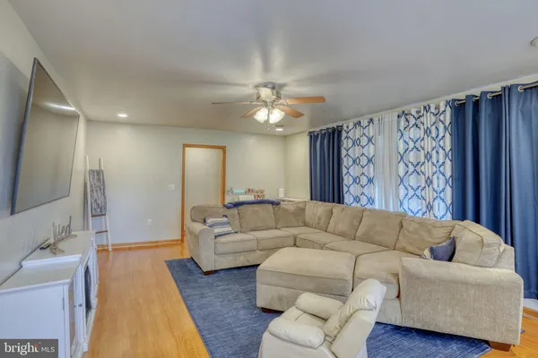 a living room with furniture and a large mirror with wooden floor