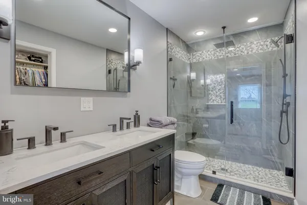 a bathroom with a shower sink vanity mirror and toilet