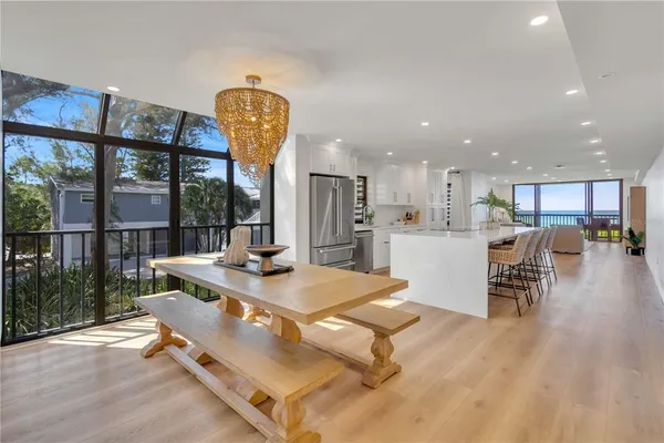 a living room with dining table furniture wooden floor and a kitchen view