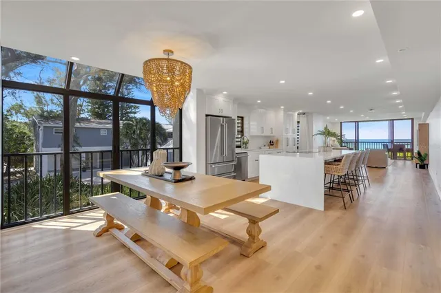 a living room with dining table furniture wooden floor and a kitchen view
