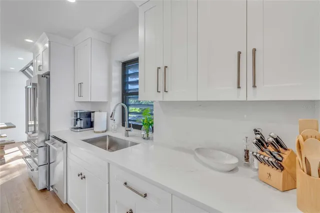 a kitchen with stainless steel appliances granite countertop a sink a stove and white cabinets