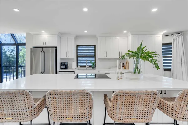 a kitchen with stainless steel appliances granite countertop a sink a stove a refrigerator and white cabinets