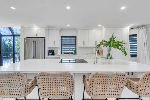a kitchen with stainless steel appliances granite countertop a sink a stove a refrigerator and white cabinets