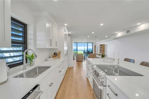 a large white kitchen with wooden floors stainless steel appliances and white cabinets