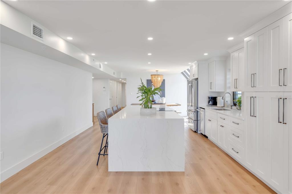 5611 Gulf Of Mexico Drive, Unit 1 Longboat Key, FL 34228 - Photo 23 of 39 a large white kitchen with wooden floors stainless steel appliances and white cabinets