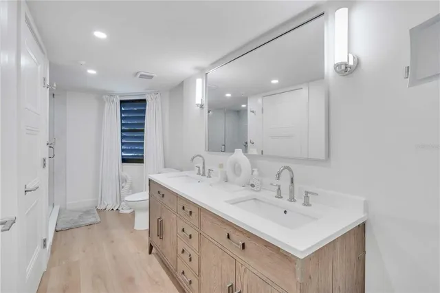 a bathroom with a sink a toilet a mirror and shower