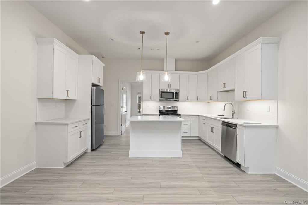 a large kitchen with white cabinets and stainless steel appliances
