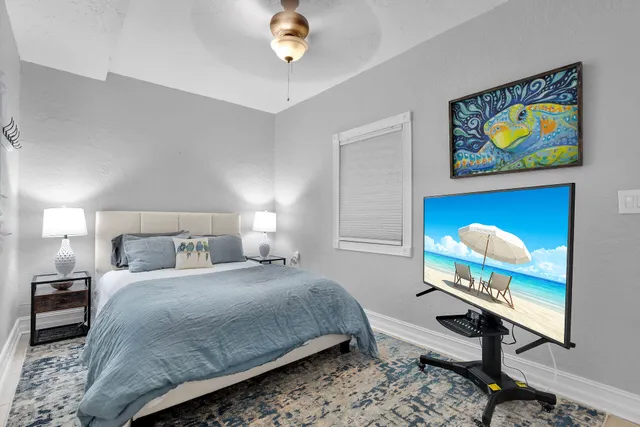 a bedroom with a bed a painting on the wall and a potted plant