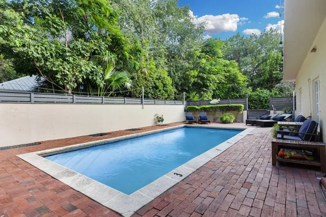 a view of swimming pool with seating space and trees in the background