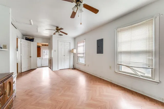 an empty room with wooden floor a ceiling fan and windows