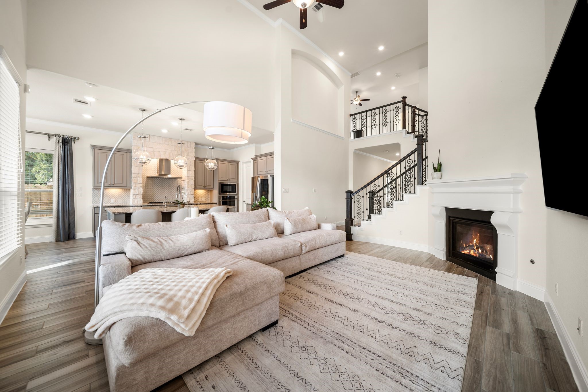 18307 Whistling Hills Road Cypress, TX 77433 - Photo 3 of 38 Double-height ceilings elevate the open kitchen, living, and dining spaces, filling the home with natural light. The expansive island anchors the layout and is perfect for entertaining.