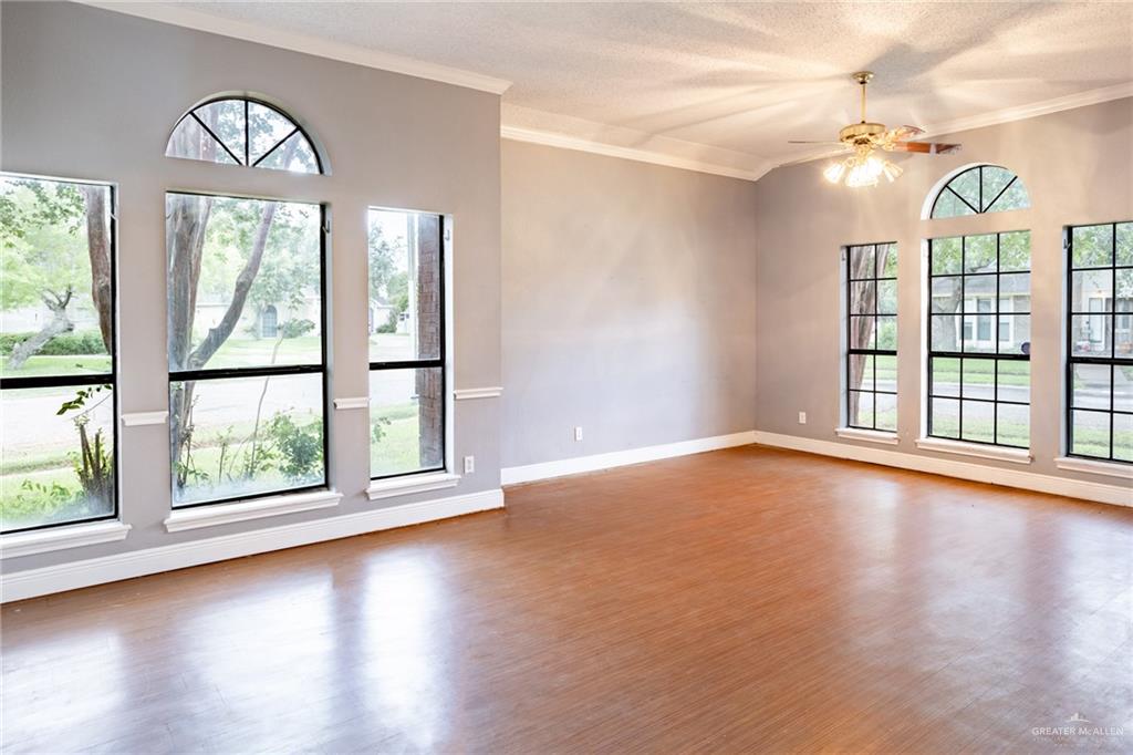 7434 Lake Como Drive Corpus Christi, TX 78413 - Photo 3 of 20 Spare room with a textured ceiling, ceiling fan, wood-type flooring, and crown molding