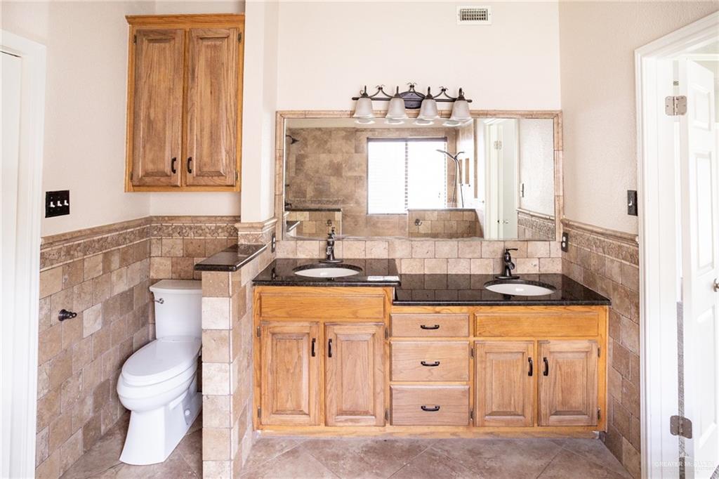 7434 Lake Como Drive Corpus Christi, TX 78413 - Photo 10 of 20 Bathroom with tile patterned floors, vanity, tile walls, and toilet