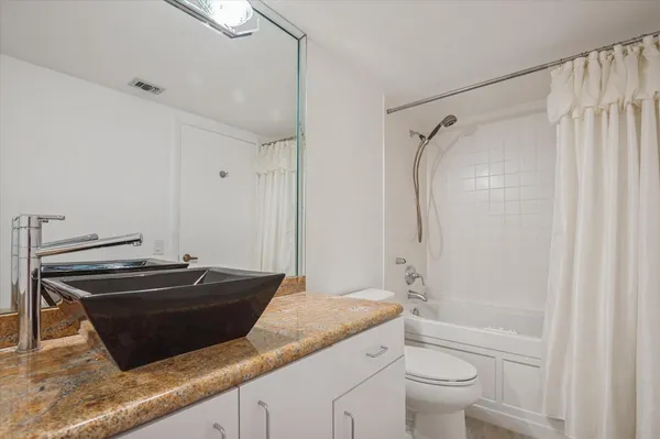 a bathroom with a granite countertop sink toilet and shower
