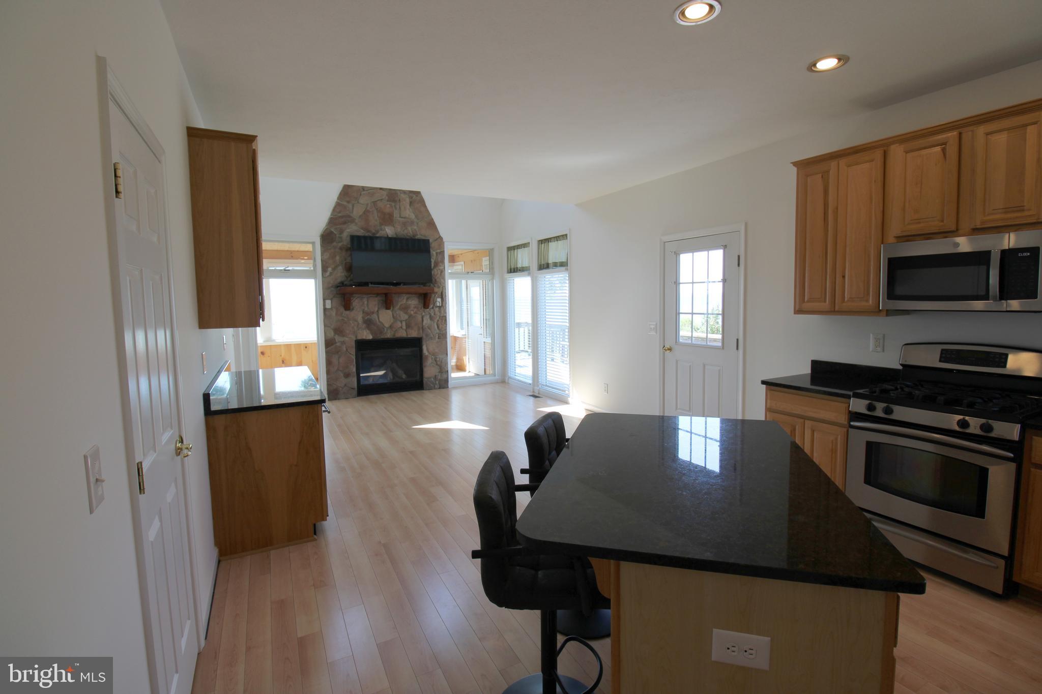 40461 Old Breton Beach Road Leonardtown, MD 20650 - Photo 17 of 61 a kitchen with a table chairs a fireplace and a window
