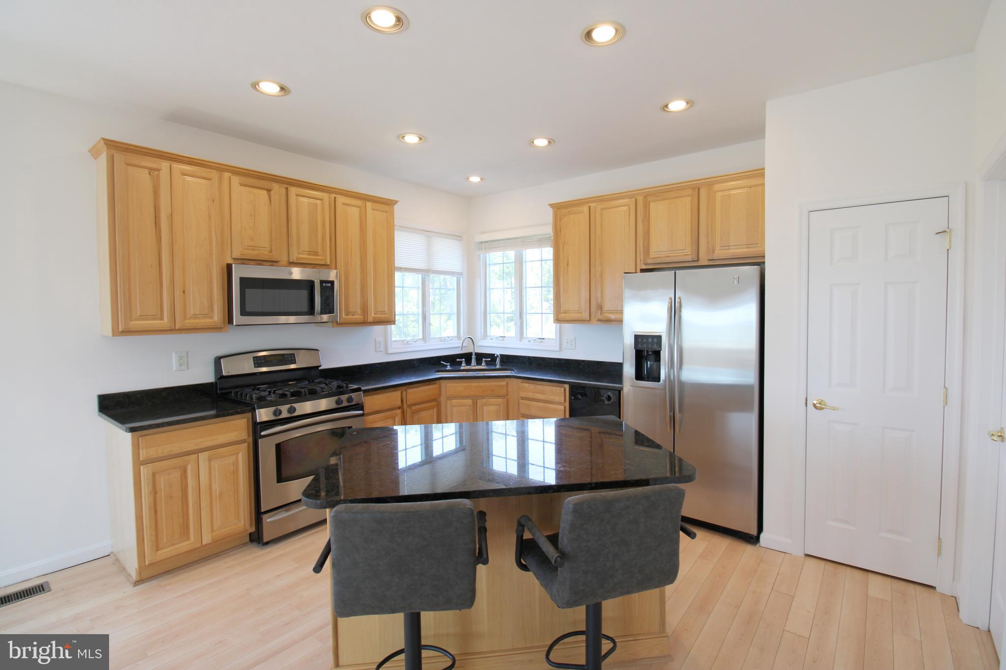 40461 Old Breton Beach Road Leonardtown, MD 20650 - Photo 23 of 61 a kitchen with stainless steel appliances granite countertop a stove a sink a microwave a refrigerator and white cabinets