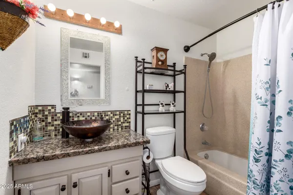 a bathroom with a granite countertop sink a toilet and shower