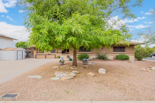 a backyard of a house with table and chairs plants and large trees