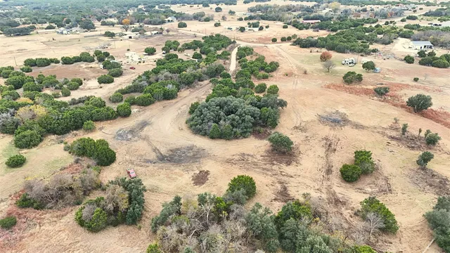 a view of a dry yard with trees in the background