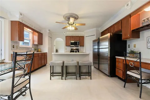 a kitchen with stainless steel appliances granite countertop a refrigerator a stove a sink a dining table and chairs with wooden floor