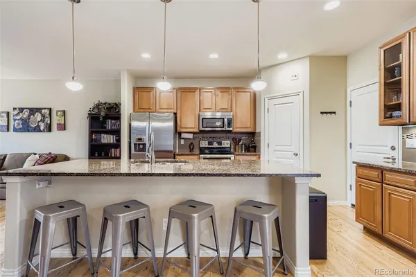 a kitchen with stainless steel appliances granite countertop a table chairs in it and wooden floors