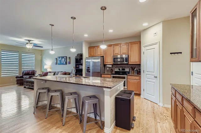 a kitchen with stainless steel appliances granite countertop a refrigerator a sink dishwasher a stove and white cabinets with wooden floor