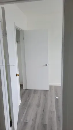 an empty room with wooden floor and white door