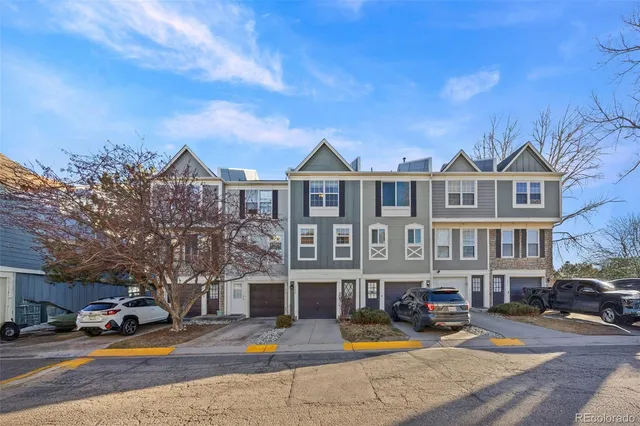 a front view of a building with lot of cars and trees