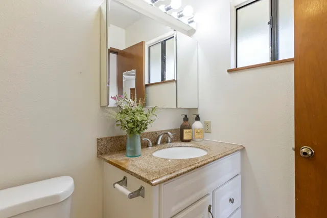 a kitchen with granite countertop a stove sink and cabinets