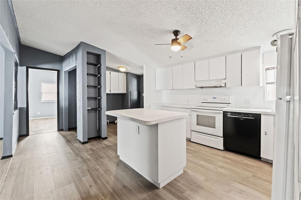 7610 County Road 663 Bushnell, FL 33513 - Photo 11 of 43 a kitchen with kitchen island white cabinets and stainless steel appliances
