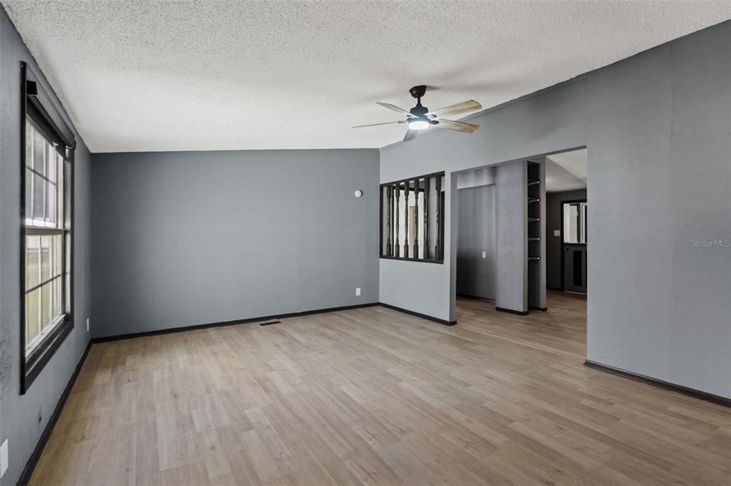 7610 County Road 663 Bushnell, FL 33513 - Photo 15 of 43 an empty room with wooden floor chandelier fan and windows