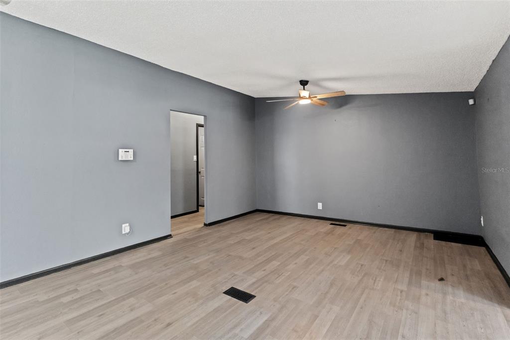 7610 County Road 663 Bushnell, FL 33513 - Photo 16 of 43 an empty room with wooden floor and chandelier fan