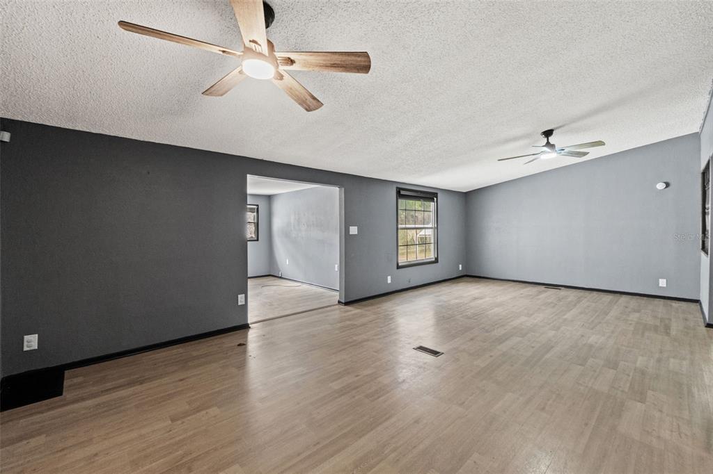 7610 County Road 663 Bushnell, FL 33513 - Photo 19 of 43 an empty room with wooden floor chandelier fan and windows