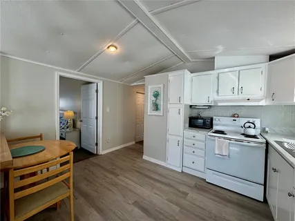 a kitchen with a stove a refrigerator and white cabinets
