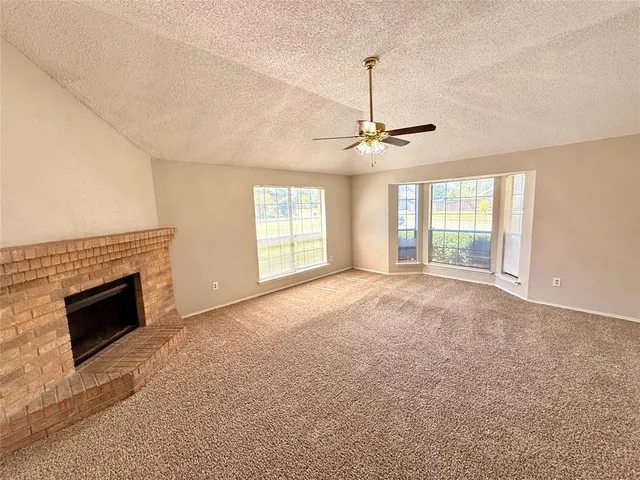 a view of an empty room with a fireplace and a window