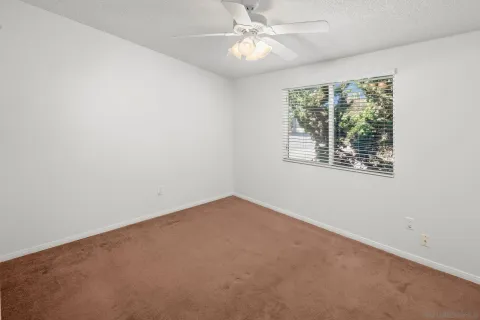an empty room with a window and a fan