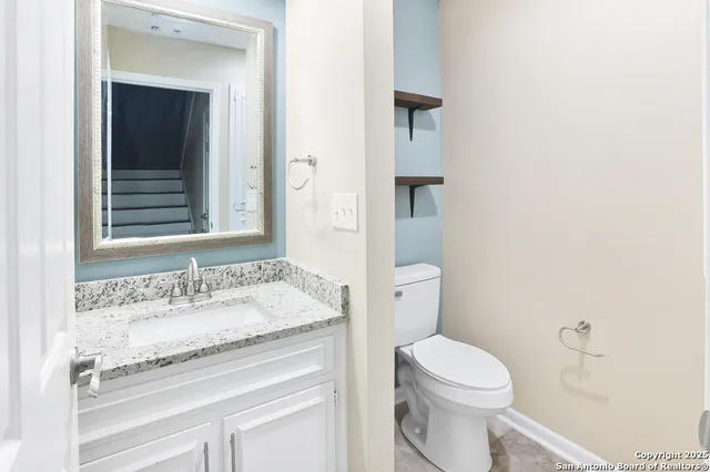 a bathroom with a granite countertop sink toilet and mirror