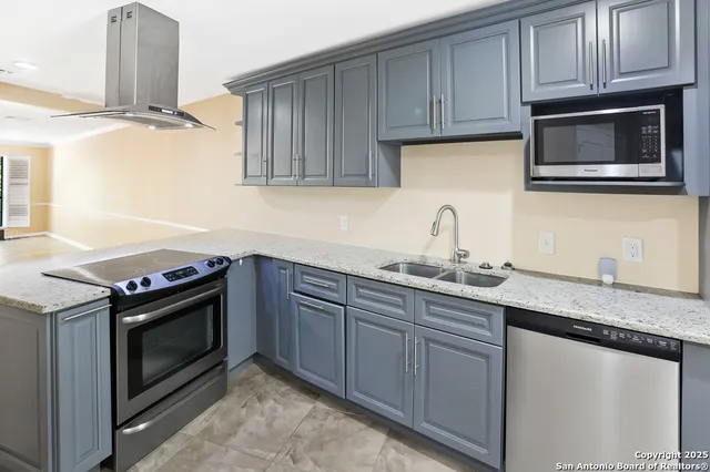 a kitchen with granite countertop a sink stainless steel appliances and cabinets