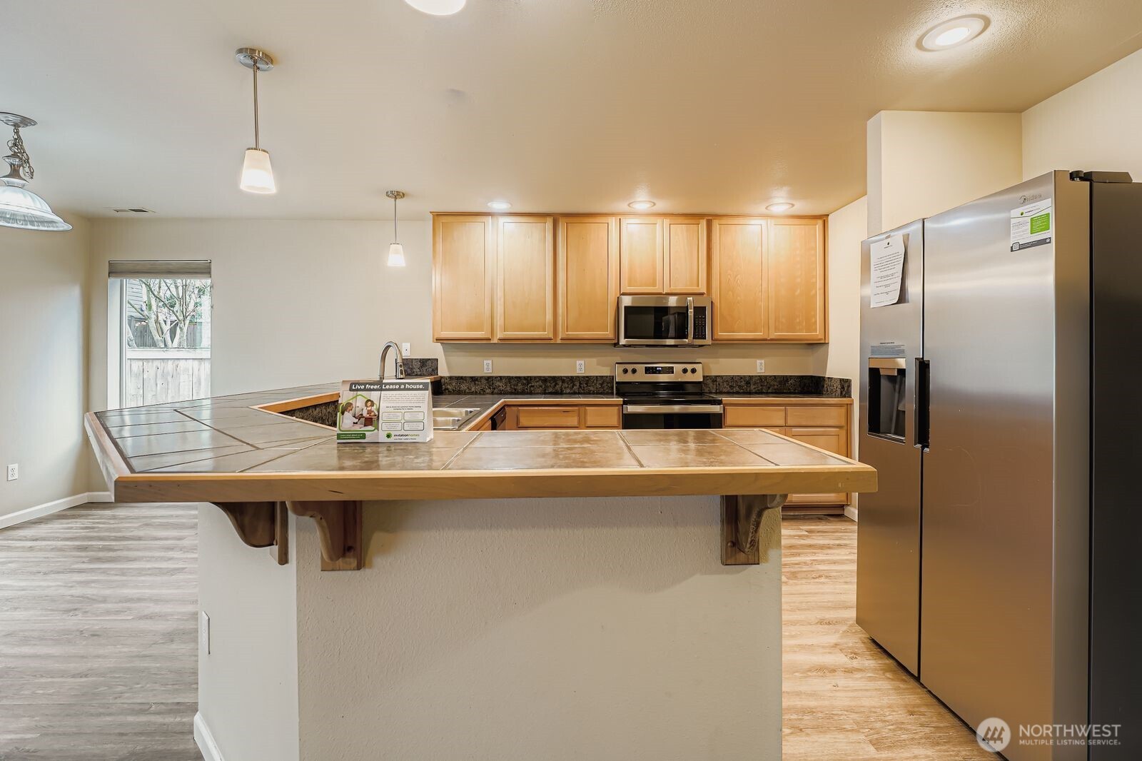 27030 228th Place Southeast Maple Valley, WA 98038 - Photo 11 of 36 a kitchen with kitchen island stainless steel appliances a sink stove and refrigerator