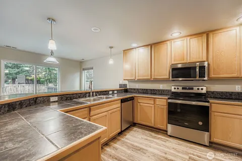 a kitchen with stainless steel appliances granite countertop a stove a sink and a microwave
