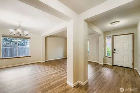 an empty room with wooden floor cabinet and windows