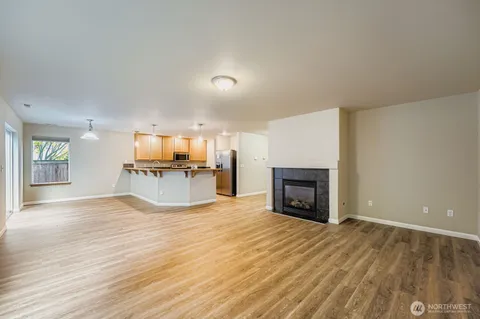 an empty room with wooden floor fireplace and windows
