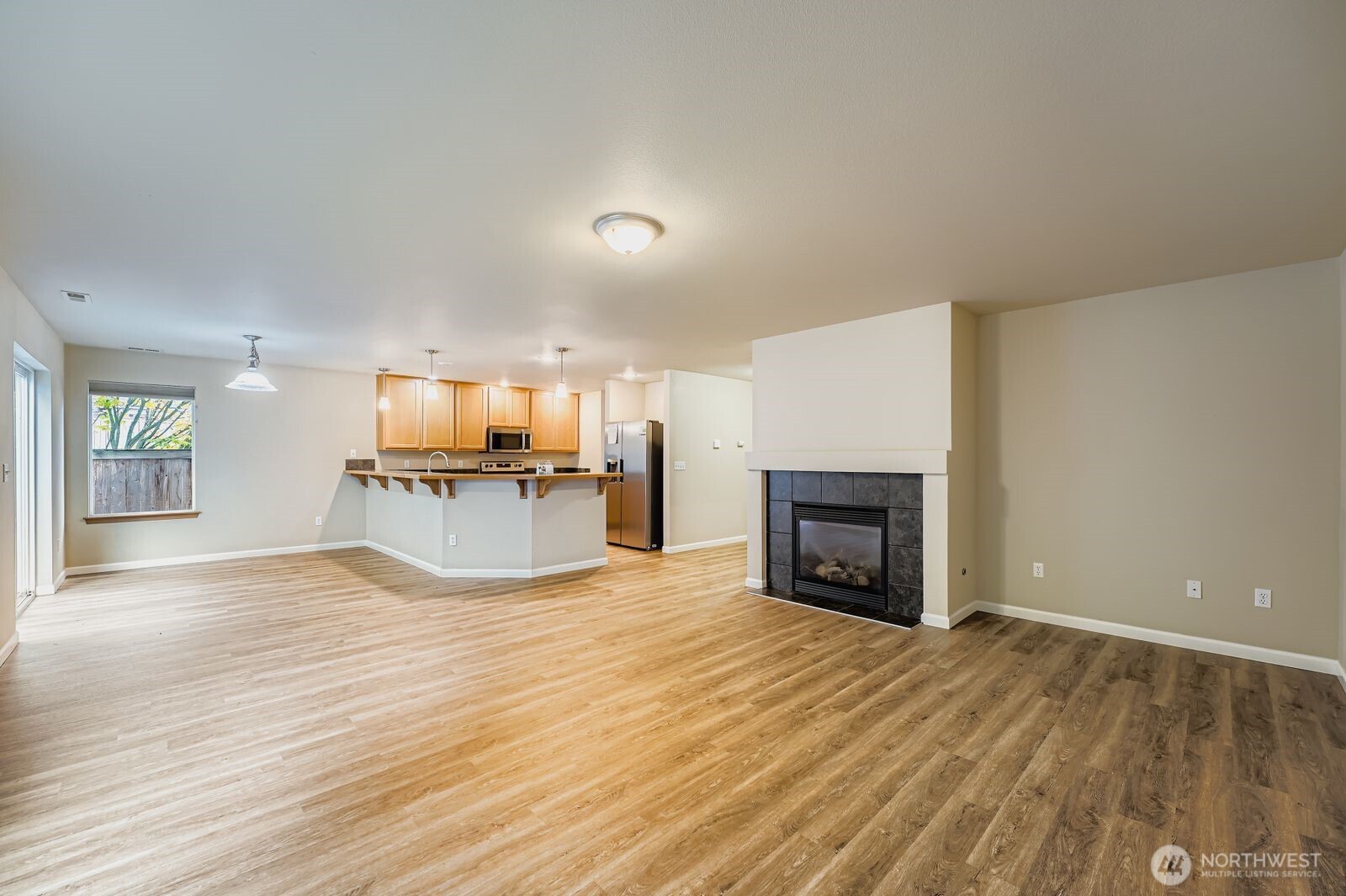 27030 228th Place Southeast Maple Valley, WA 98038 - Photo 6 of 36 an empty room with wooden floor fireplace and windows
