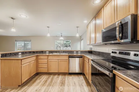 a kitchen with stainless steel appliances a sink dishwasher a stove top oven a refrigerator with island and cabinets