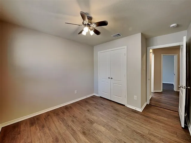 an empty room with wooden floor fan and windows