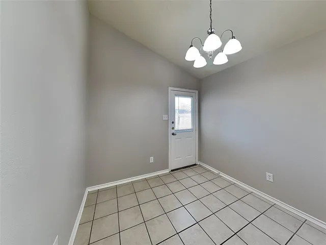 a view of an empty room with a chandelier fan