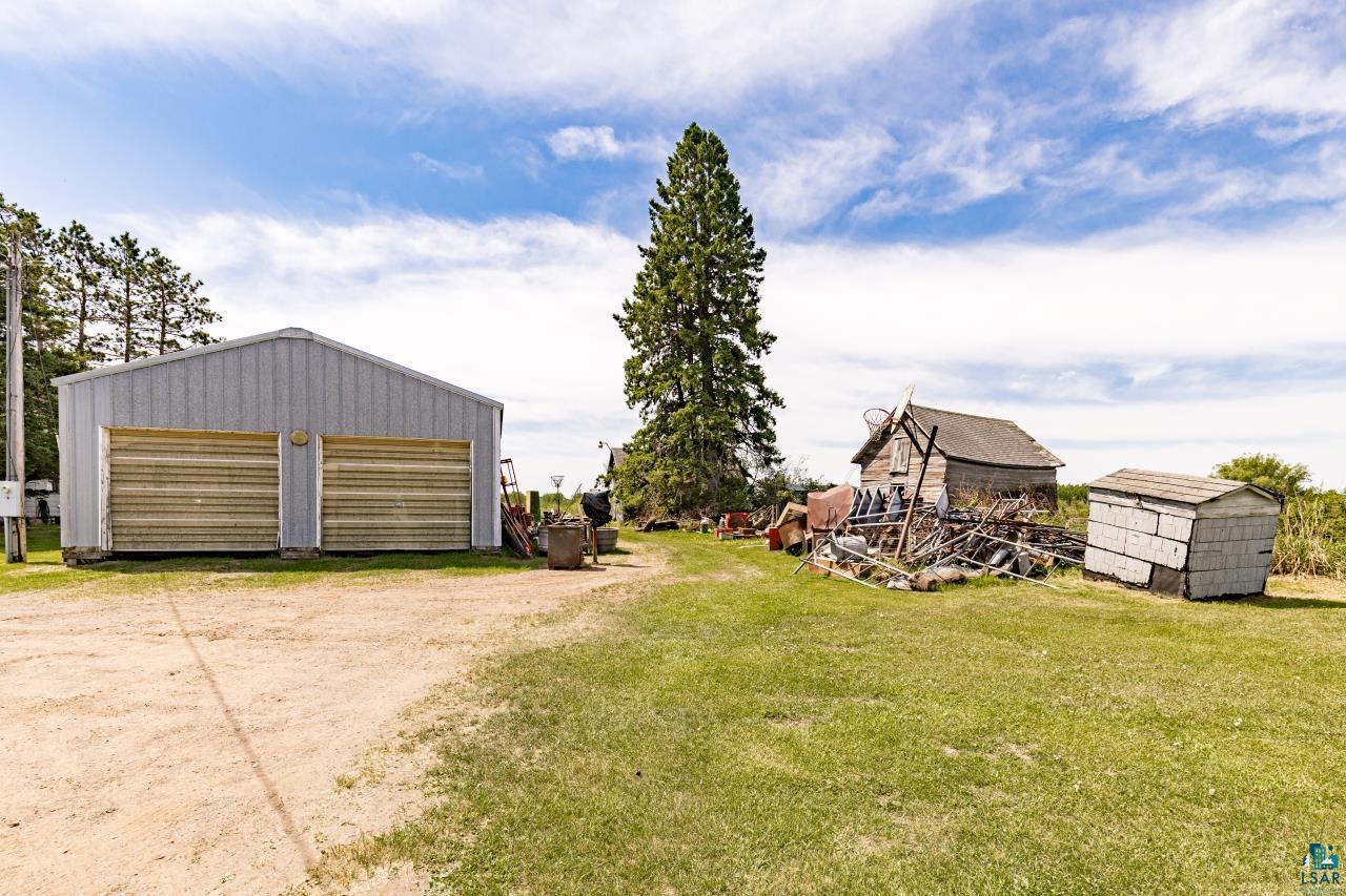 6606 Metso Road Kettle River, MN 55757 - Photo 64 of 84 Metal-clad outbuilding featuring two garage doors, surrounded by green space and a dirt path