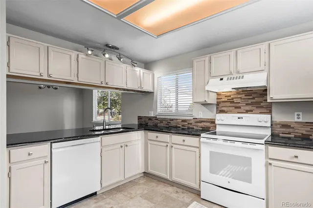 a kitchen with granite countertop white cabinets and white appliances