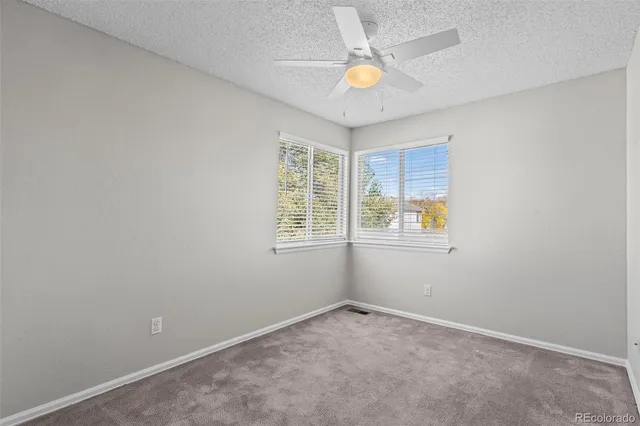 an empty room with window and ceiling fan