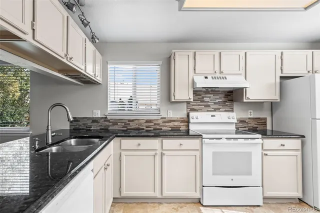 a kitchen with white cabinets stainless steel appliances a sink and a window